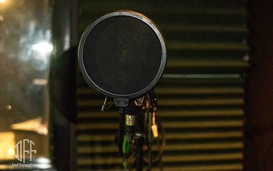 A microphone sits on top of a table in a recording studio.